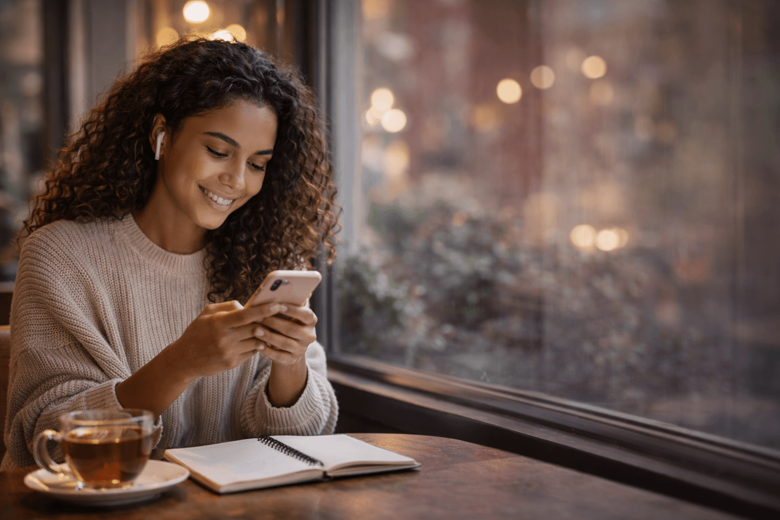 Woman smiling while using phone at a cozy café